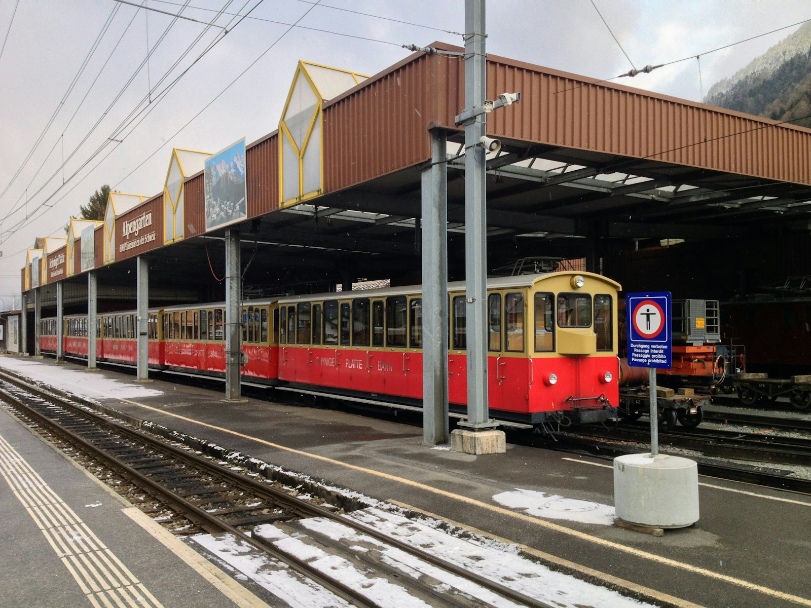 a red and yellow train pulling into a train station